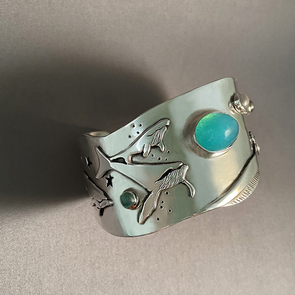 Bracelet by Nadine Zenobi showing a whale with green and blue stones